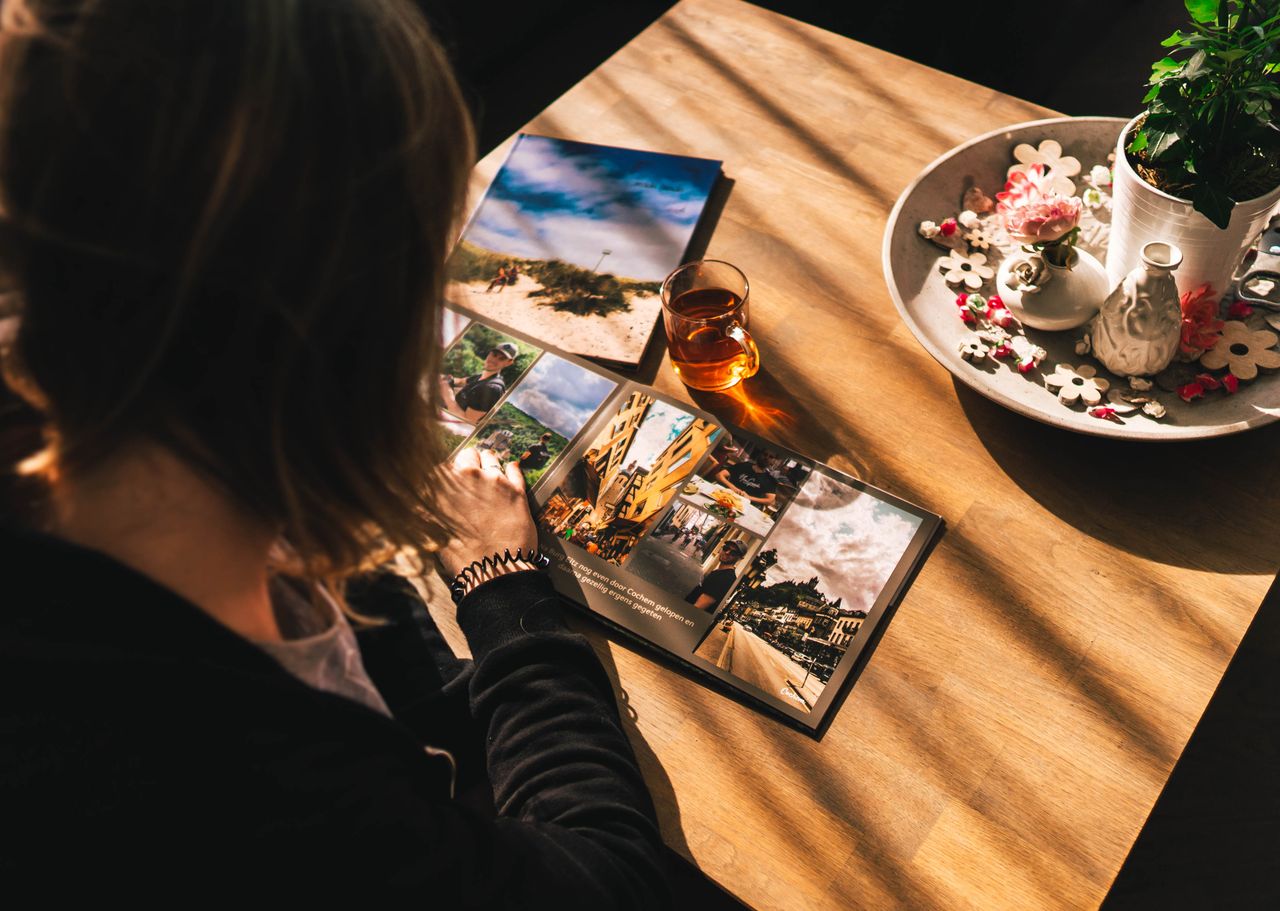 Cozy scene of a woman viewing a travel photo book with warm sunlight.